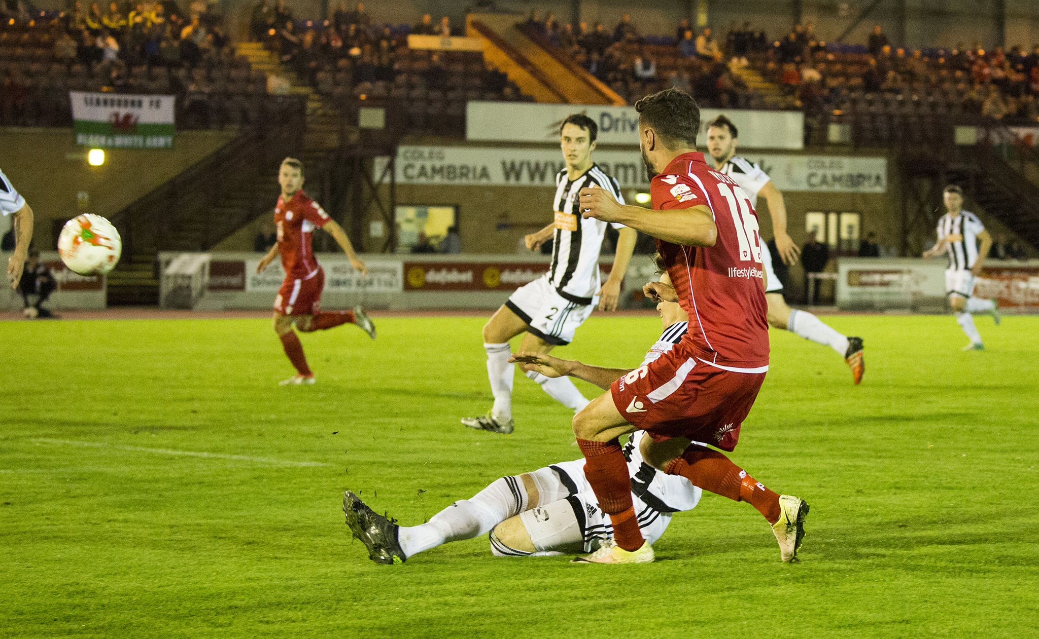 Nathan Woolfe flashes a cross across the face of the Llandudno goal - © NCM Media